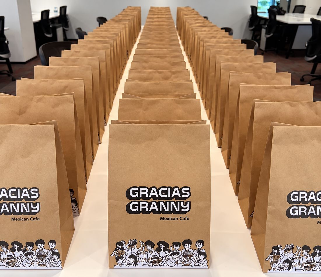Rows of Gracias Granny paper bags lined up on a long table in an office